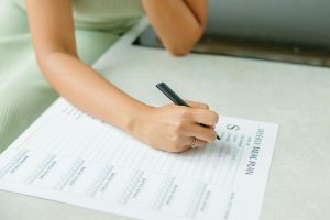 Woman writing meal ideas on a weekly meal plan template.