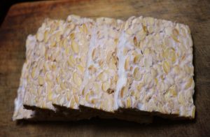 Tempeh is white and beige, and looks like a block of pressed beans before it’s cooked.