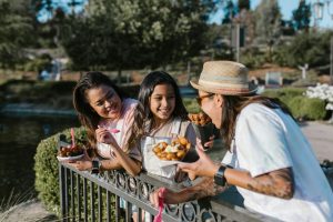 A smiling family sharing snacks at a zoo.