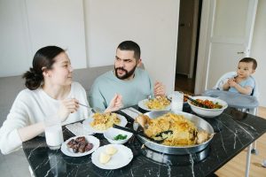 Parents with a toddler son in a high chair, eating dinner at home.