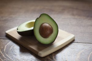 Green avocado, sliced in half, showing large brown pit.