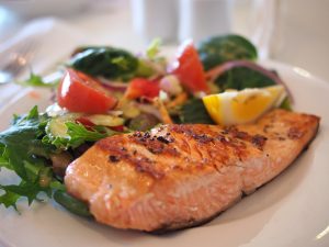 Grilled salmon with a lemon wedge and mixed green salad.