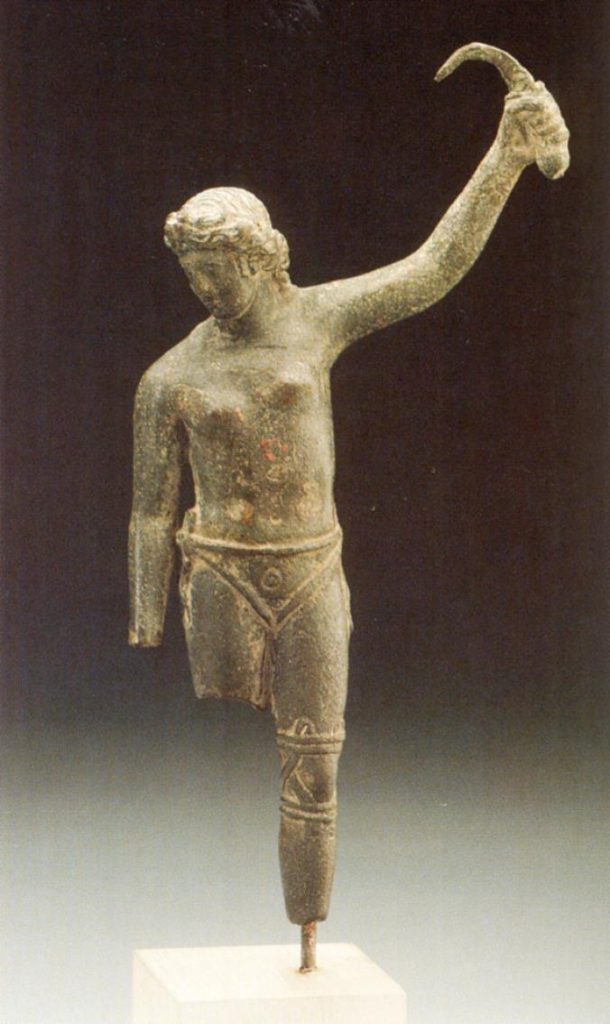 A roughly 2,000 year-old statuette of bare-chested female gladiator in a loincloth performing for one or more publics in Ancient Rome believed to be holding a sica (short, curved blade) with raised arm.