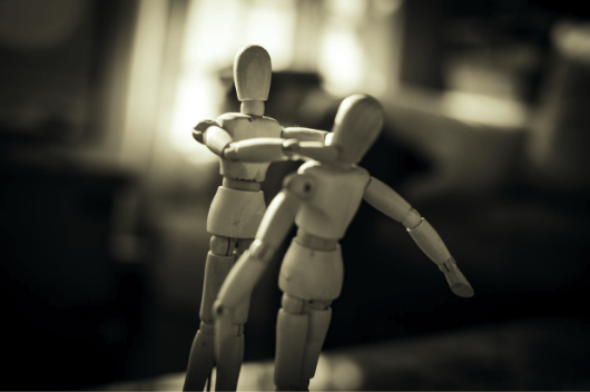 Two white figurines fighting with each other against a black background