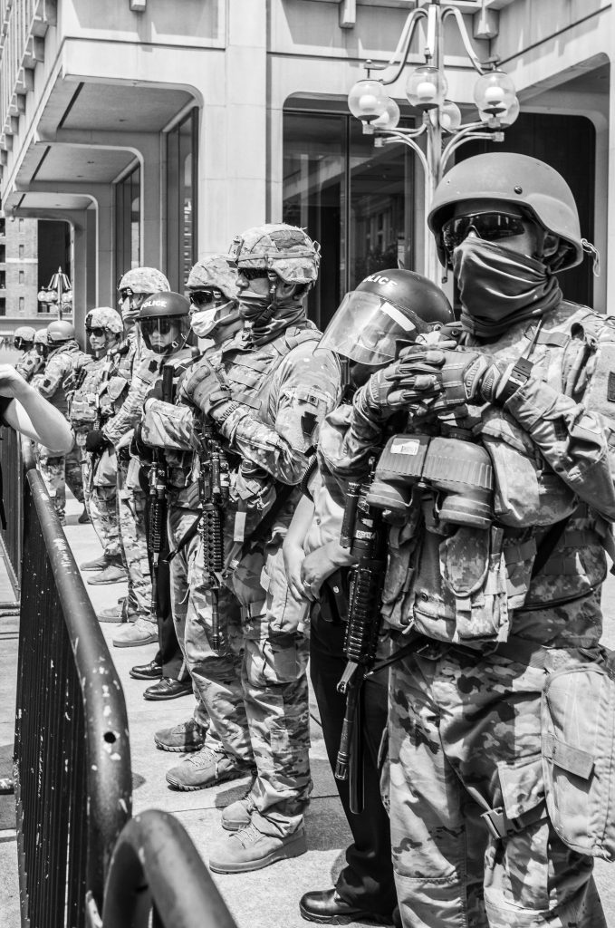 A black and white image of an american police force that is armed and dressed almost like it was a military