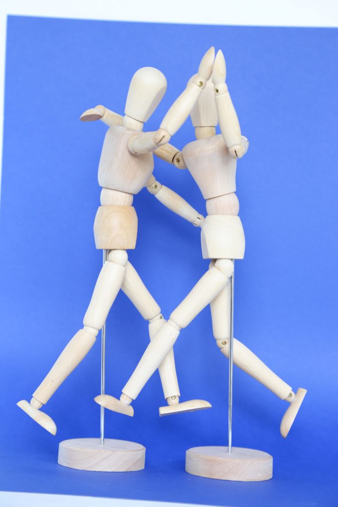 Two white figurines dancing with each other against a blue background