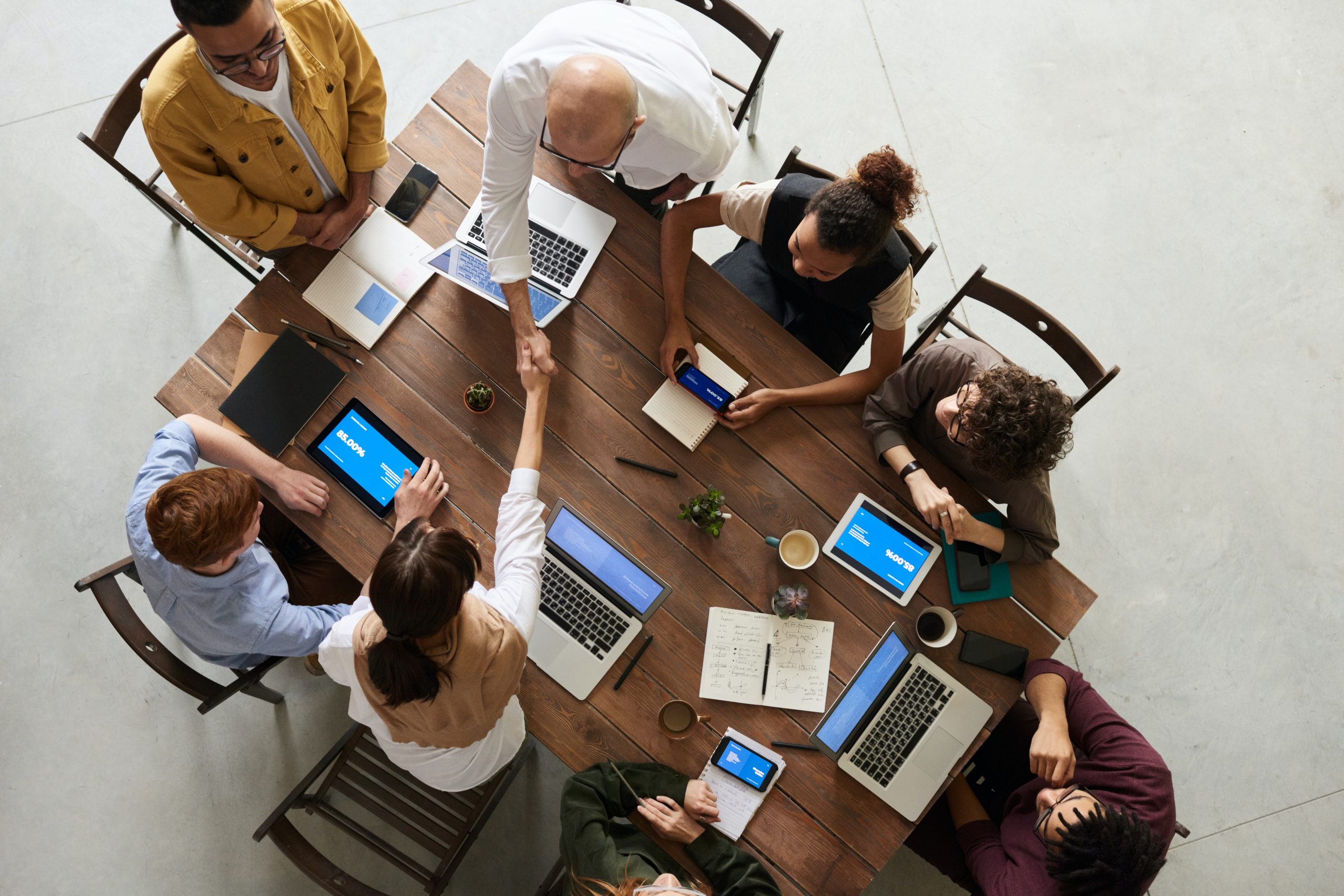 Overhead shot of students sitting around a table with their digital devices